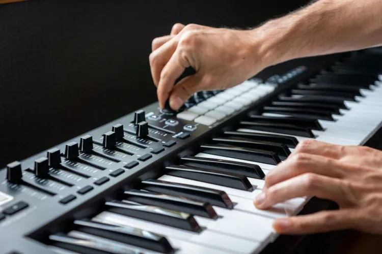 Persona con teclado midi de 88 teclas tocando teclas y botones