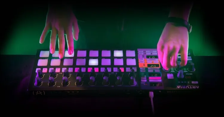 controlador midi Arturia BeatStep Pro con pads y knobs y manos de persona tocándolo o usandolo