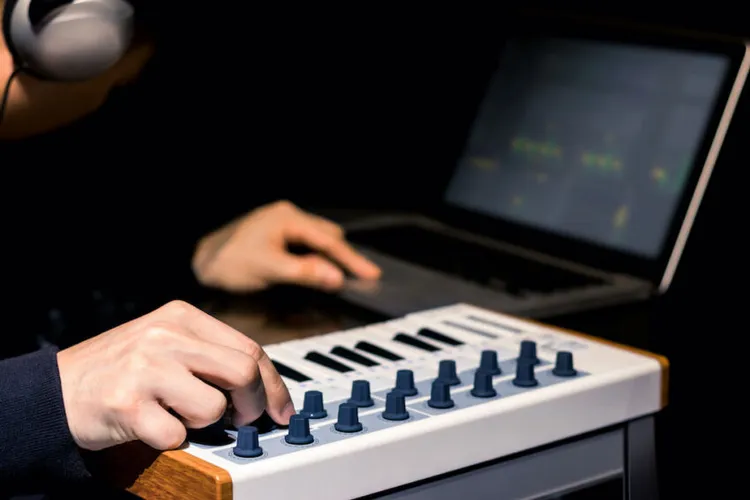 persona tocando un teclado midi mini con ordenador