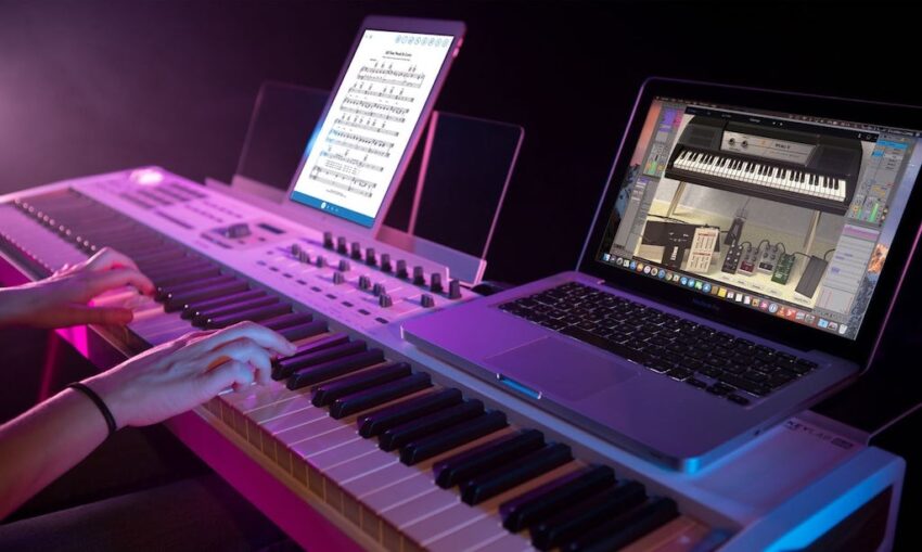 Persona tocando piano midi de 88 teclas con ordenador macbook y ipad